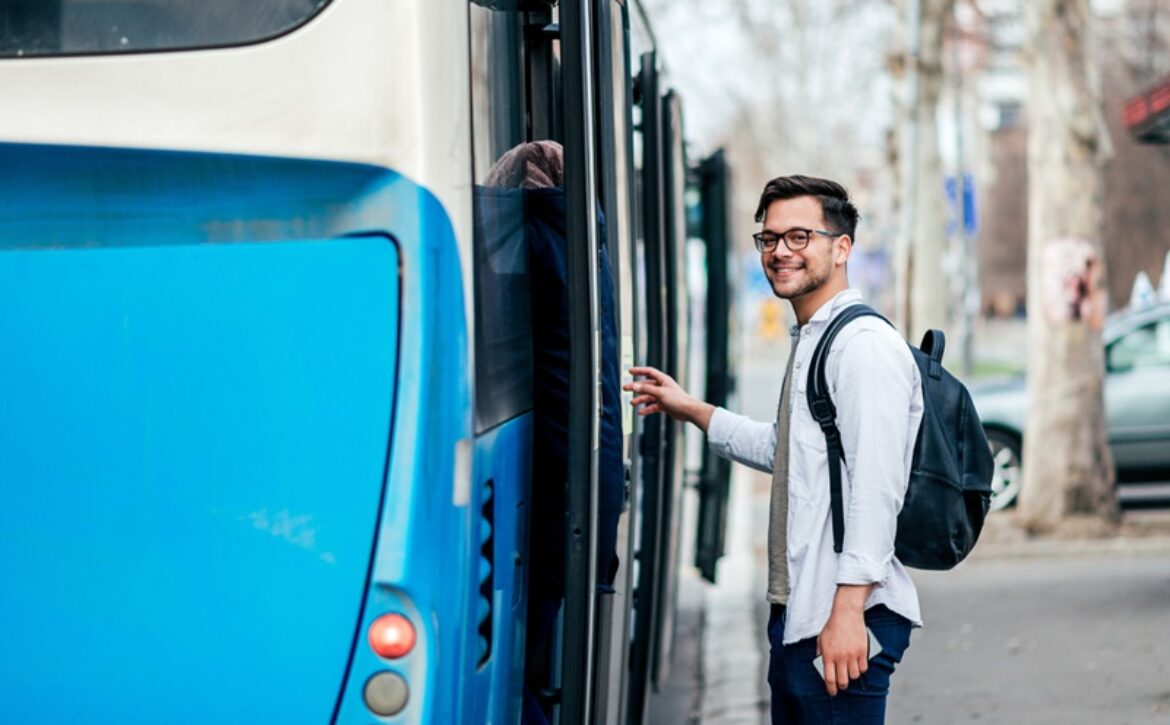 Handsome smiling young man getting into bus.